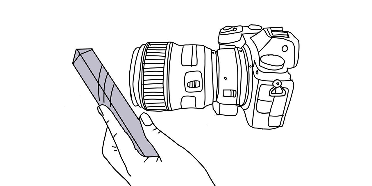 Ilustracija fotoaparata s prizmo pred objektivom.